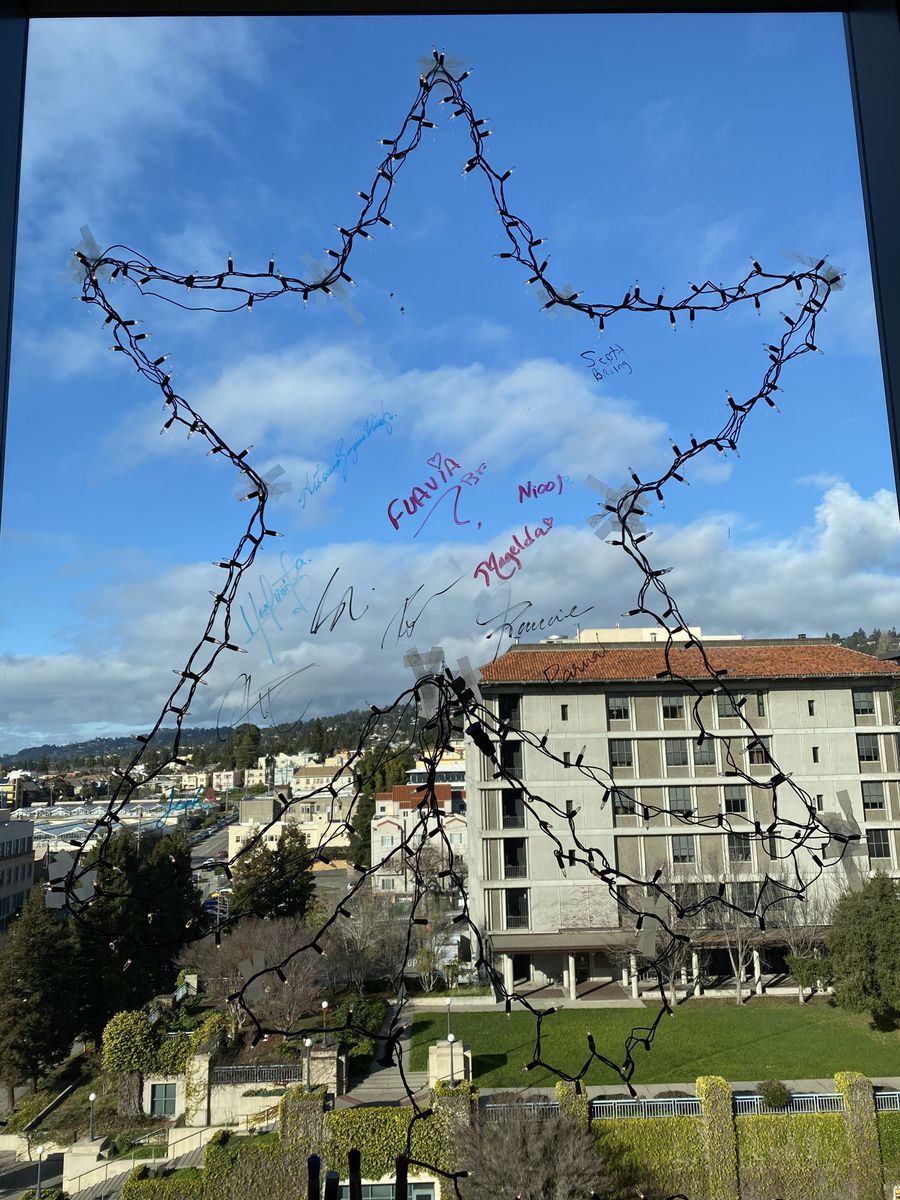 A star of fairy lights signed by lab members on a window overlooking UC Berkeley